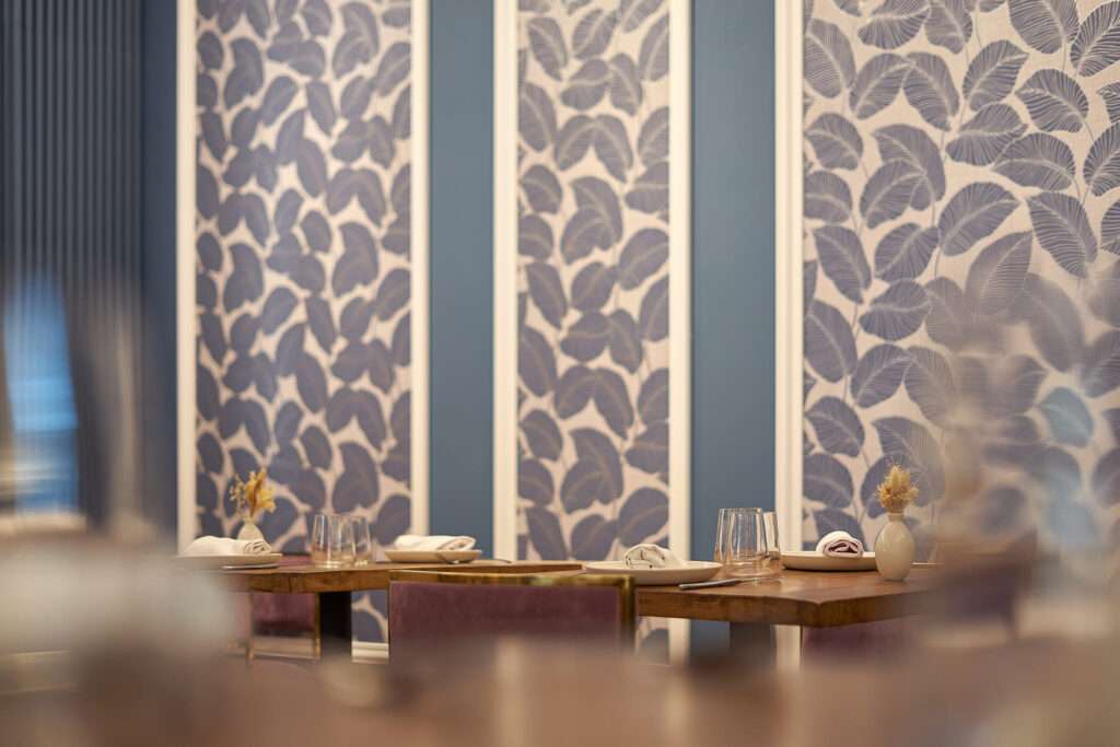 Sala interior de Redondo en Boca con paredes enteladas en azul y mesas puestas